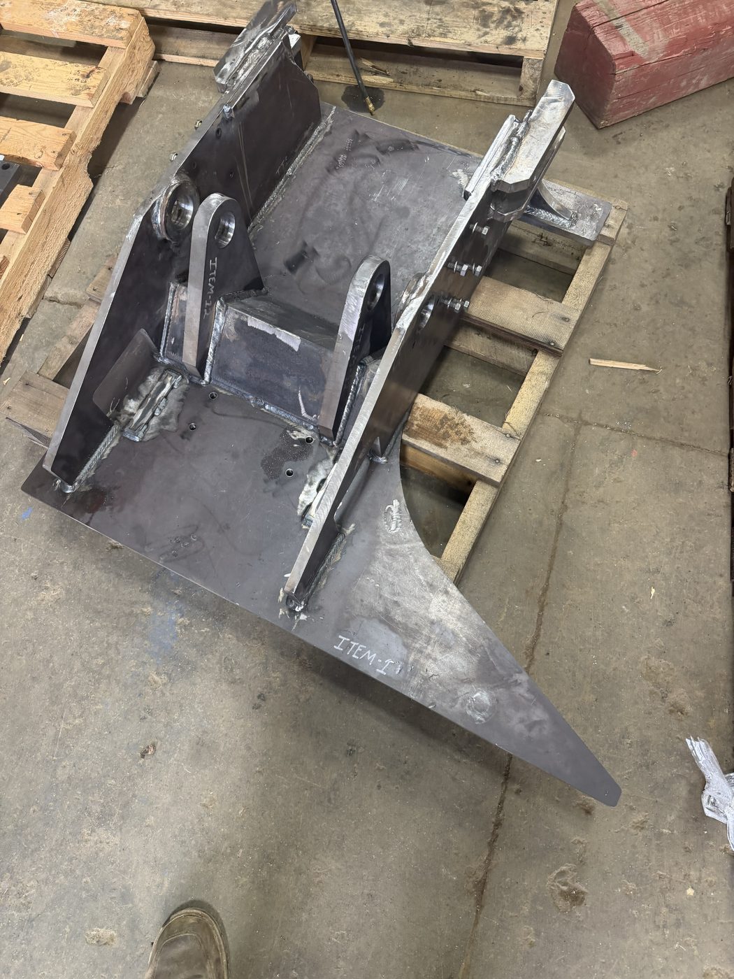 Custom fabricated bare steel drill rig top-head weldment with pin bosses on a pallet
