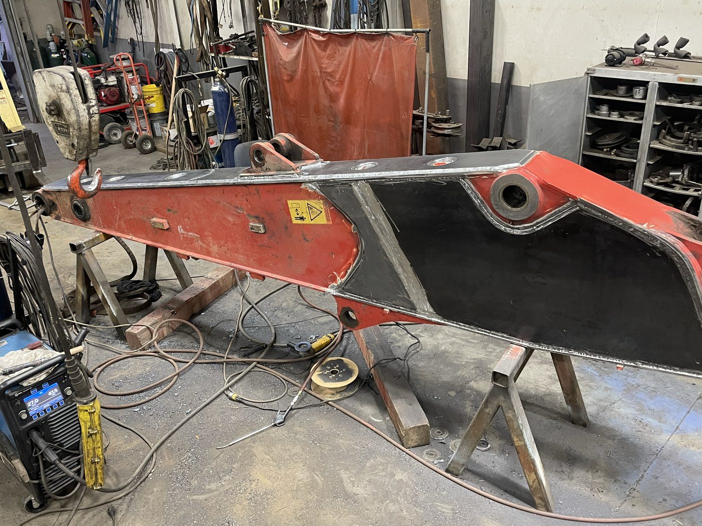 In-shop reinforcement of a red Link-Belt excavator stick with new steel plate welded in